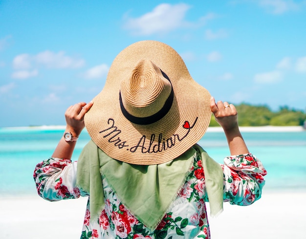 Foto vista posteriore di una donna che indossa un cappello contro il mare