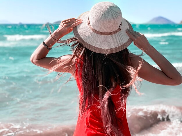 Rear view of woman wearing hat looking at sea