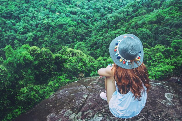 Photo rear view of woman wearing hat sitting on mountain