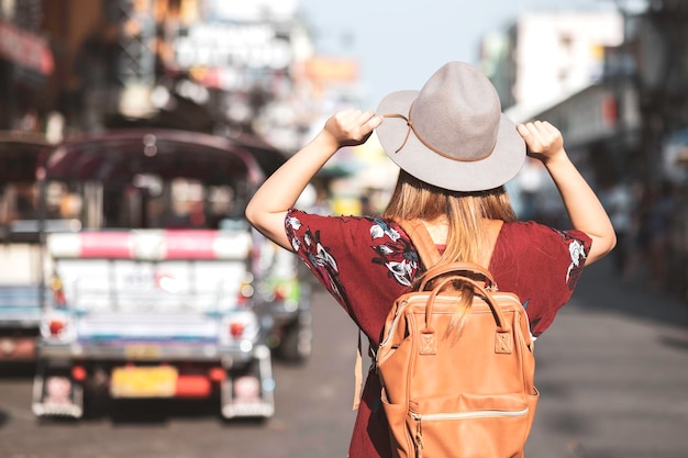 Rear view of woman wearing hat standing on road in city