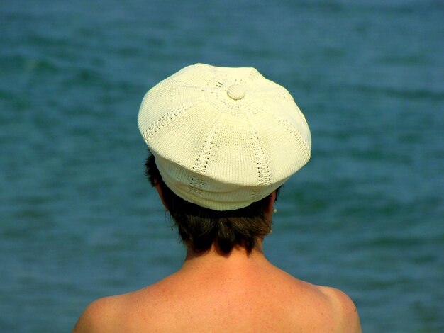 Rear view of woman wearing white woolen cap against sea