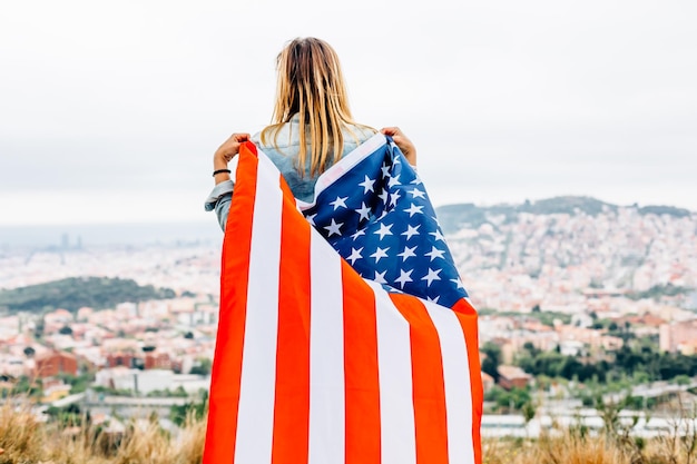 Foto vista posteriore di una donna con la bandiera americana in piedi contro il cielo