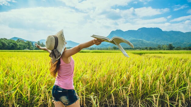 Rear view of woman with arms outstretched on field against sky