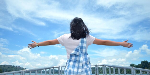 Photo rear view of woman with arms outstretched standing against cloudy sky
