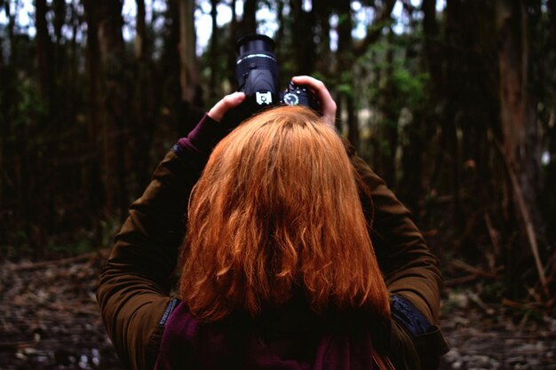 Photo rear view of woman with arms raised in forest