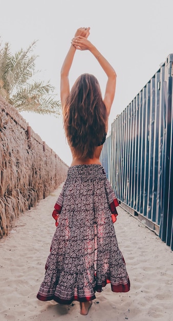 Photo rear view of woman with arms raised standing against sky