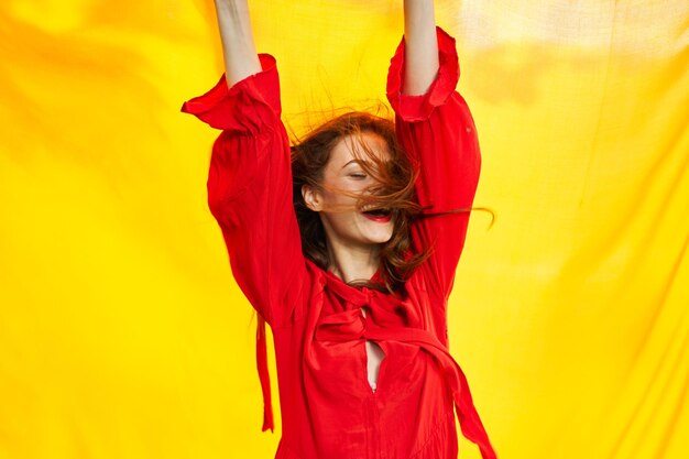 Rear view of woman with arms raised standing against yellow background