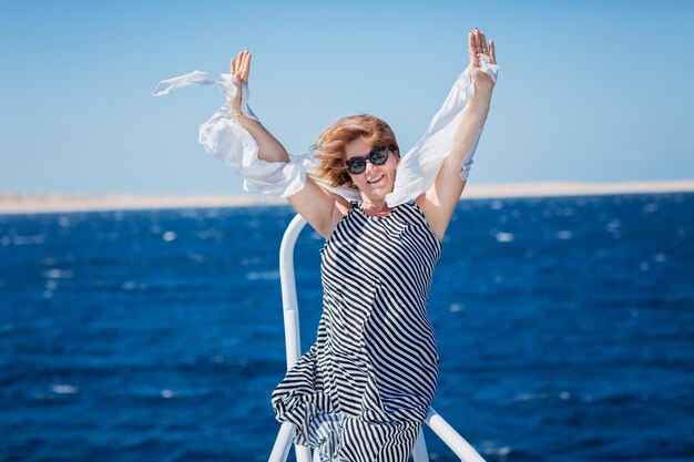 Rear view of woman with arms raised standing at beach