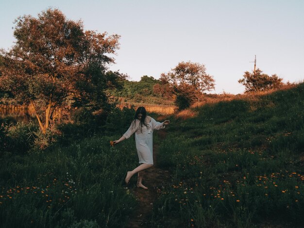 Photo rear view of woman with arms raised standing on field against clear sky