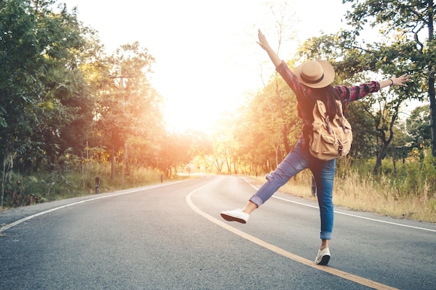 Photo rear view of woman with backpack jumping on road