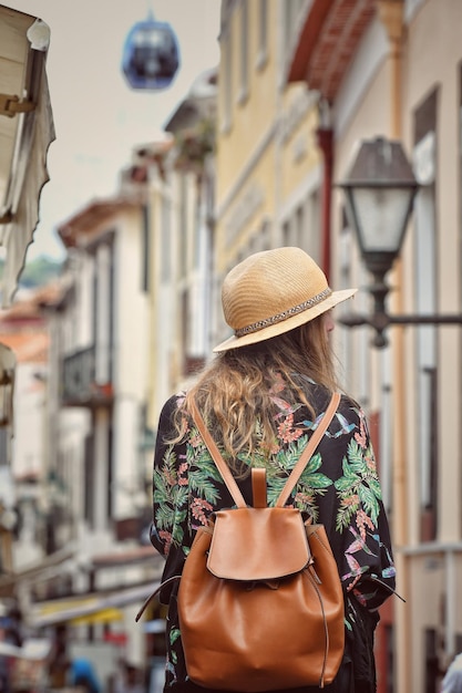 rear view of woman with backpack walking amidst buildings in city