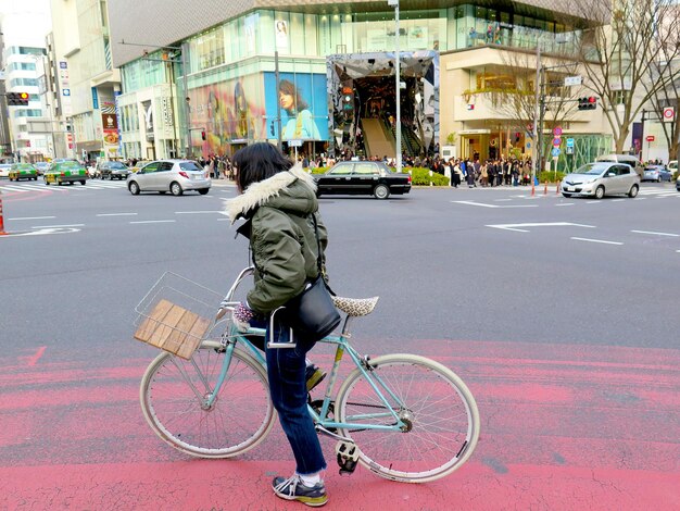 Photo rear view of woman with bicycle on road in city
