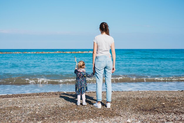 Rear view of woman with dog on beach against sky