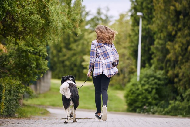 Foto vista posteriore di una donna con un cane che cammina