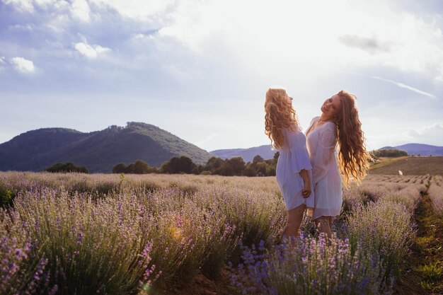 Foto vista posteriore di una donna con fiori sul campo contro il cielo