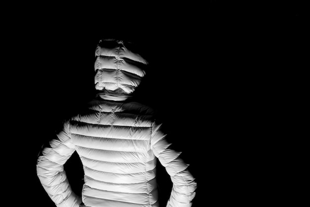 Rear view of woman with hooded jacket standing in park at night