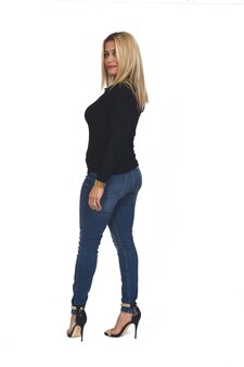 Vista posteriore di una donna con jeans e scarpe col tacco che guarda l'obbiettivo su sfondo bianco