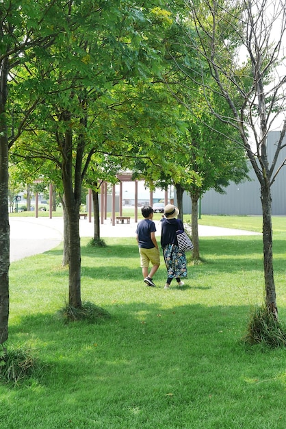 公園で歩いている息子と一緒にいる女性の後ろの景色