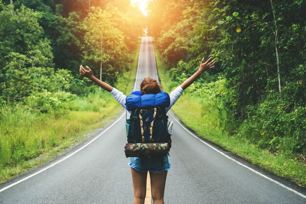 Foto vista posteriore di una donna con un ombrello sulla strada nella foresta