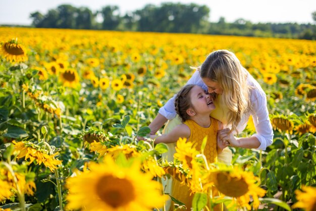 畑で黄色い花をかせる植物と女性の後ろの景色