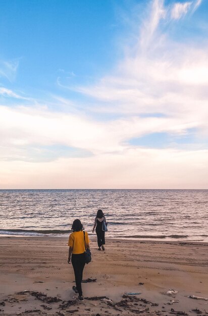 Rear view of women on beach against sky