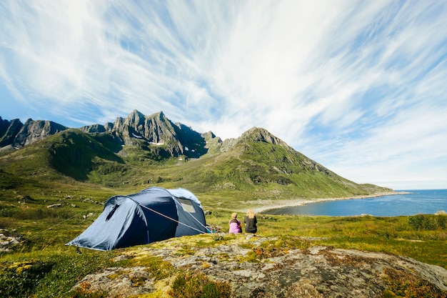 rear view of women by tent against mountains