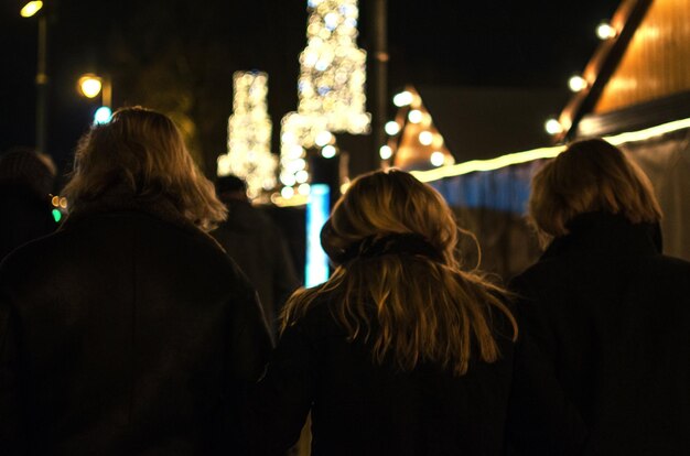 Foto vista posteriore di donne che guardano le luci di natale di notte