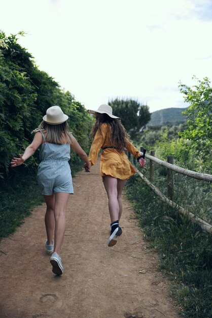 Vista posteriore di donne che corrono su una strada di terra contro il cielo