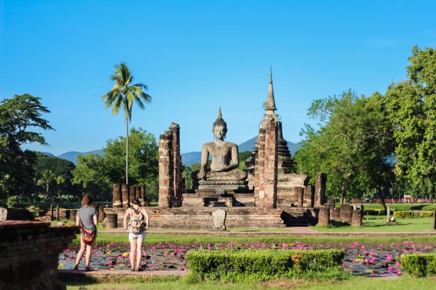 Rear view of women standing against buddha statue