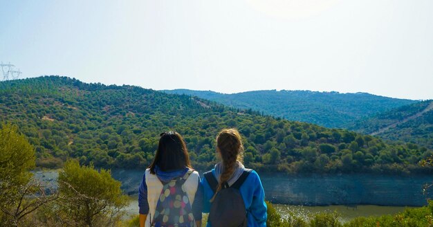 Rear view of women standing against mountains