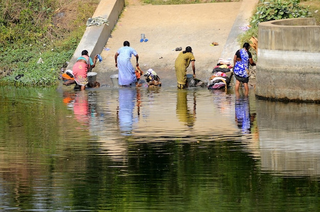 Foto vista posteriore di donne che lavano i vestiti sulla riva del fiume