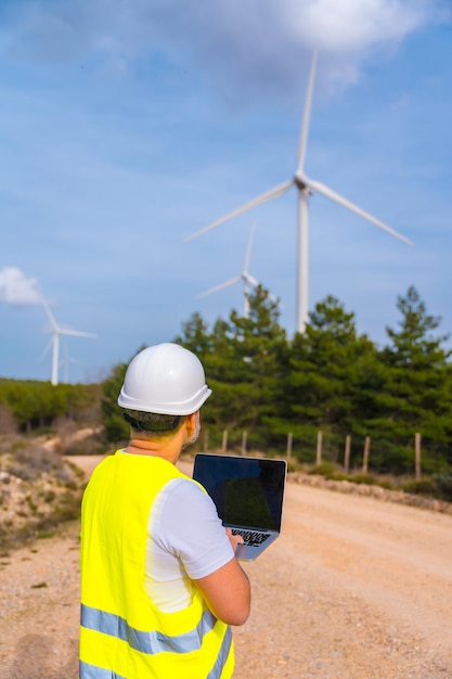 Photo rear view of worker of a wind energy park using laptop