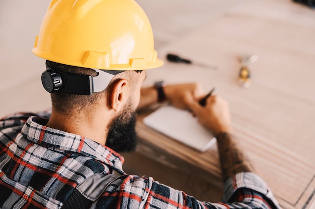 Rear view of worker writing down calculations for material