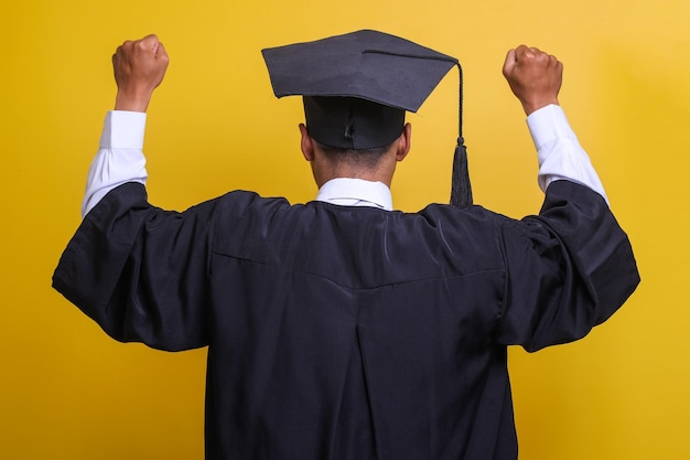 Rear view young Asian graduated man celebrating victory and success with raised arm