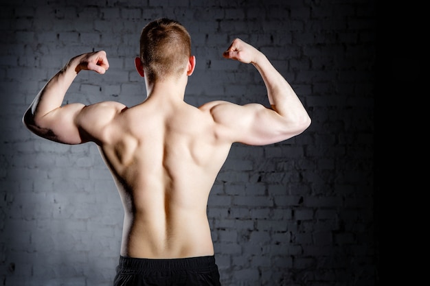 Vista posteriore del giovane attraente uomo muscolare indoeuropeo bodybuilder