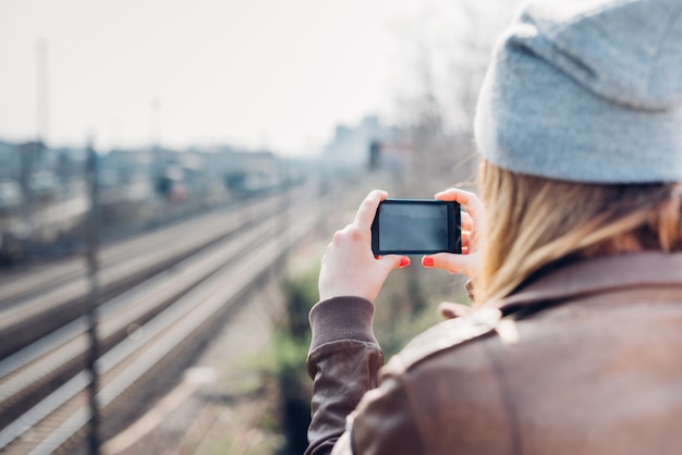 写真を撮っている街の若い美しいブロンドのヒップスターの女性の後ろ姿