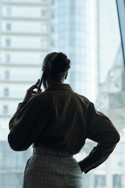 Rear view of young black woman with hair bun standing in front of window