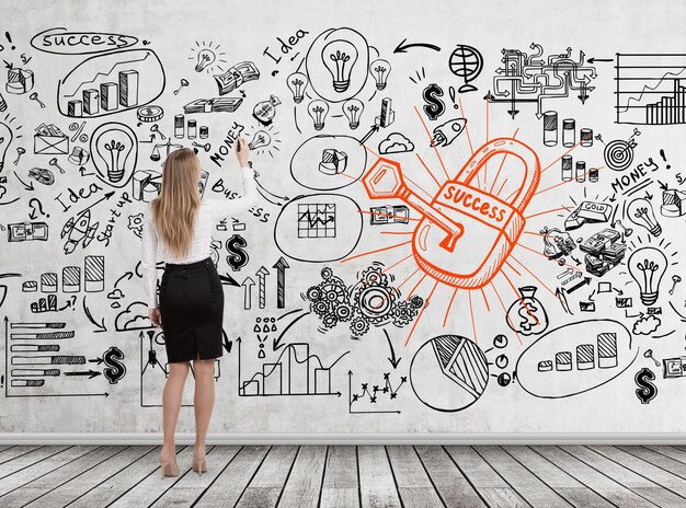 Rear view of a young blond businesswoman drawing a business scheme, a lock and a key on a concrete wall.