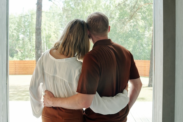 Rear view of young couple embracing each other while dreaming of future into new house