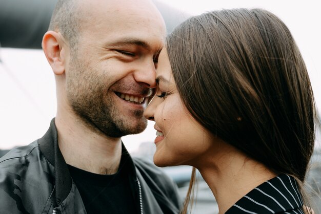 Foto retrovisione di una giovane coppia che si siede dal lato di un lago che tocca le loro teste nell'amore. coppia in amore ad un appuntamento seduto all'aperto vicino a un lago con un bicchiere di vino.