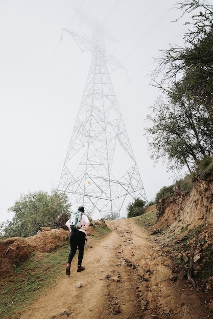 Rear view young latin plus size woman with backpack on, climbing a hill and hiking in a foggy day