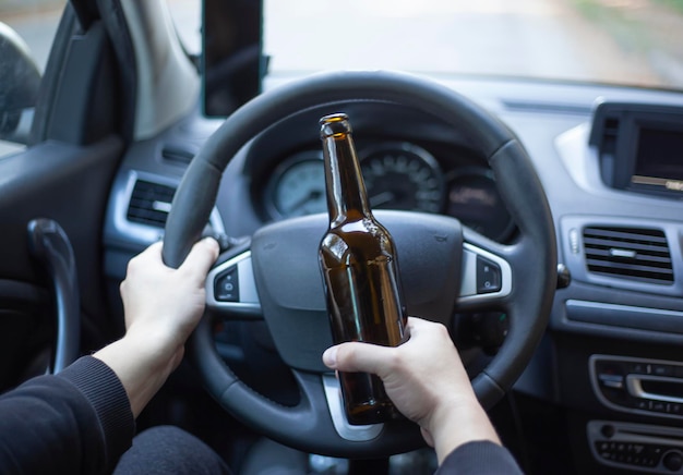 Rear view of a young man driving a car while drinking beer Selective focus