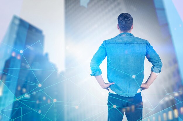 Rear view of young man wearing jeans shirt looking at blurred city with glowing network interface. Toned image double exposure