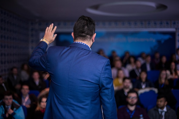 Retrovisione del giovane uomo d'affari di successo nella sala conferenze d'affari con presentazioni pubbliche. udienza in sala conferenze. circolo dell'imprenditoria