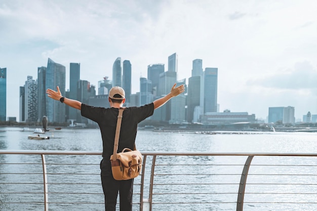 Rear view of young tourist man relaxing with her arms raised to her head enjoying looking view