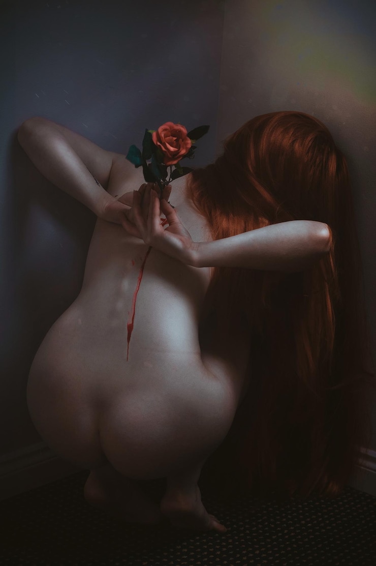 Фотография задний вид молодой женщины с розой на спине на сером фоне