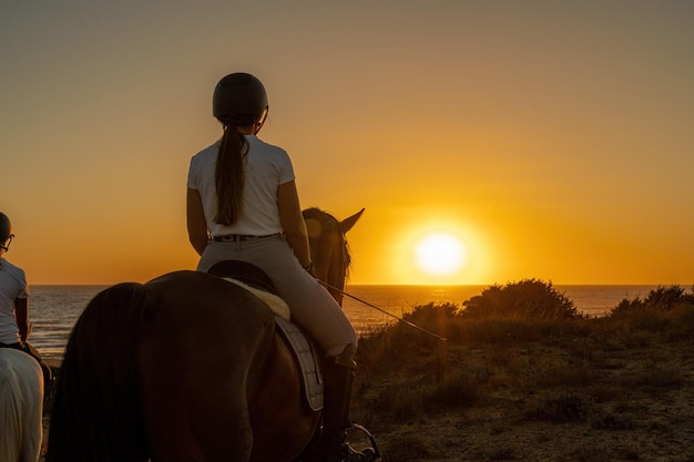 夕日を見て馬に乗った若い女性の後姿