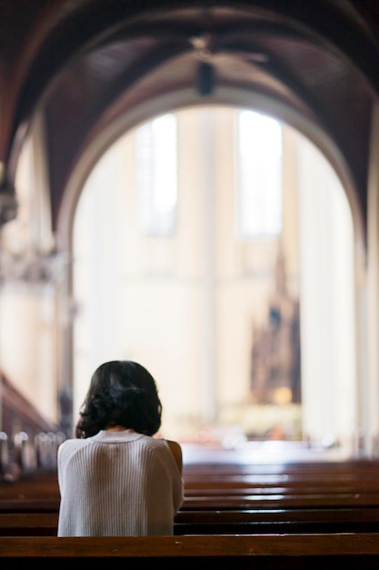 Rear view of young woman praying in the church