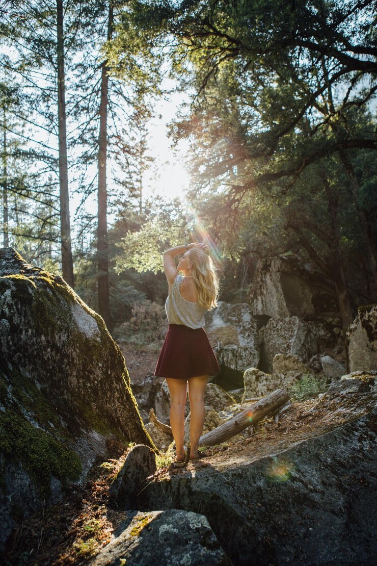 Photo rear view of young woman standing on rock in forest
