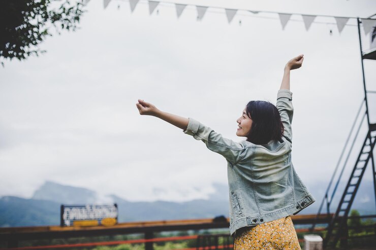 Photo 空に向かって立っている若い女性が腕を伸ばしている後ろの景色